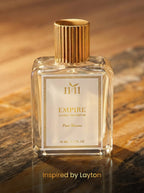Perfume bottle labeled '11:11 Empire' on a marble surface with a warm background.